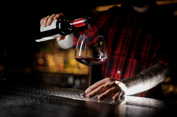 Fototapeta na wymiar Bartender pourring a wine from a bottle to a glass