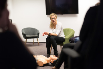 Instructor teaching first aid cardiopulmonary resuscitation course and use of automated external defibrillator on voluntary CPR workshop.