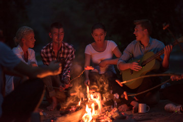 young friends relaxing around campfire