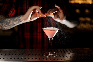 Professional bartender adding a zest juice to a Cosmopolitan cocktail