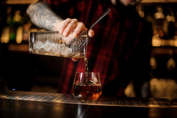 Fototapeta na wymiar Barman pouring fresh drink into a whiskey dof glass