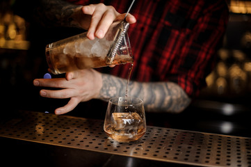 Fototapeta na wymiar Bartender pouring fresh drink into a whiskey dof glass