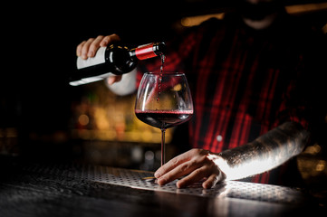 Fototapeta na wymiar Barman pouring red wine into the burgunya glass