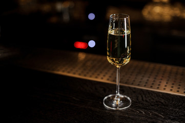 Elegant champagne glass with sparkling wine on the dark bar counter