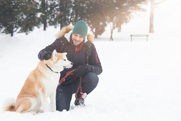 Man with akita dog pet in park on snowy day. Winter concept