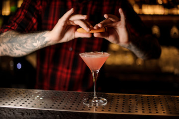 Barman sprinkling orange peel juice into a Cosmopolitan cocktail