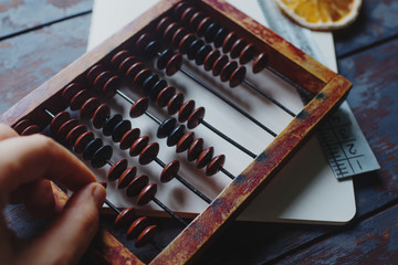 vintage abacus with notebook, pen and dried orange slices on rustic wooden table, hugge concept,...