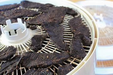 Closeup of dried spiced deer jerky slices on a dehydrator