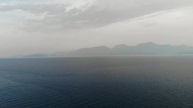 The drone is flying towards the island. Flying camera over the sea towards the island. Sea view of the Islands. Islands in fog. Aerial view. 4K