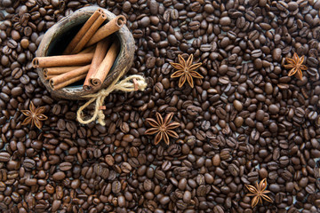 Coffee beans background, cinnamon rolls in a jug, anise spice.