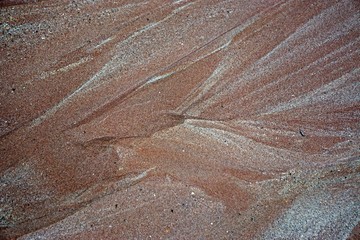 Patterns in the red and white sands on a beach.
