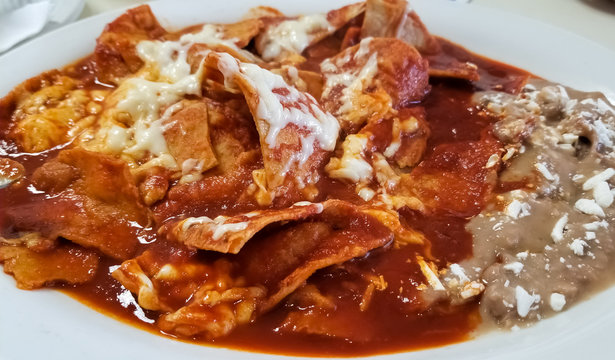 Delicious chilaquiles, typical Mexican food with beans, cheese and hot tomato sauce over traditional tortilla.