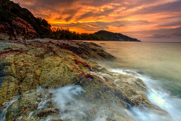 A long exposure picture Beautiful Scenery cloudy Sunset With Stone and wave As Foreground