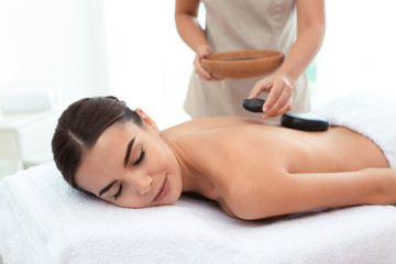 Obraz na płótnie Canvas Beautiful young woman getting hot stone massage in spa salon