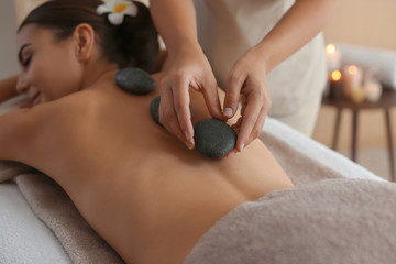 Obraz na płótnie Canvas Beautiful young woman getting hot stone massage in spa salon