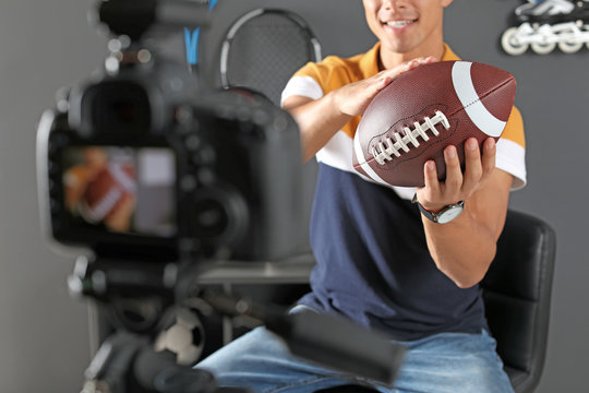 Sport blogger with ball recording video on camera at home