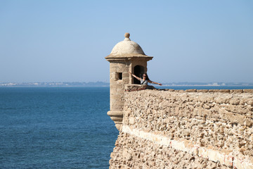 Woman posing at a small tower at a castle near the sea