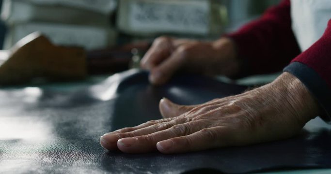 Close up of a shoemaker working a fabric in a shoe factory he is using the italian tradition. 