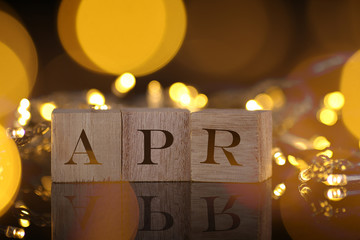 Month Concept, front view shows wooden block written April with light and bokeh background