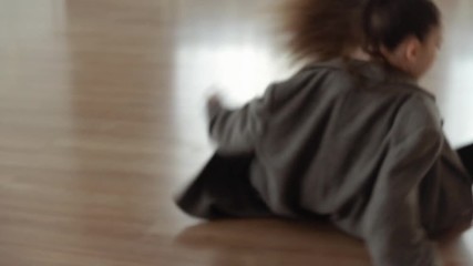 A little girl for a dance class. Girl in a gray coat dancing in the dance hall. Slow motion