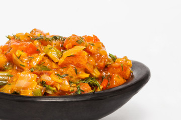 Traditional Colombian sauce called hogao served in a black ceramic dish isolated on white background