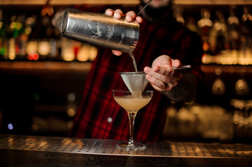 Bartender pourring a Daiquiri achoholic drink from the cocktail steel shaker