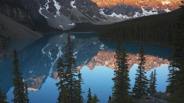 a sunrise tilt up view of a calm moraine lake at banff national park in canada