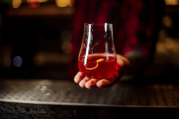Bartender serving glass of a red Sazerac cocktail