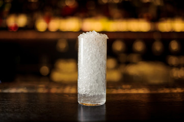 Cylindrical cocktail glass of crushed ice standing on the bar stand