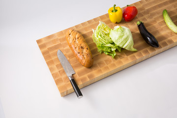 a cutting board and a knife, bread, cabbage, eggplant, green pepper, cucumber