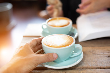 Hand Women and man put a Latte arts coffe hot coffee on wooden table.barista love art concept.