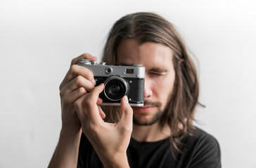 Handsome young bearded man with a long hair and in a black shirt holding vintage old-fashioned film...