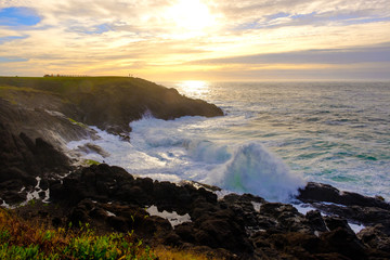 Ocean waves crashing onto the rocks in the sunset