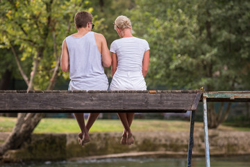 couple enjoying watermelon while sitting on the wooden bridge