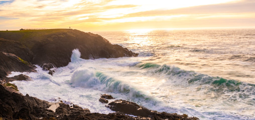 Ocean waves crashing onto the rocks in the sunset