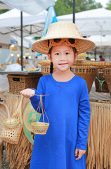 Cute little Asian kid girl wearing farmer hat with holding thai style candy in hand.