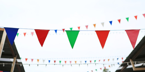 Multicolored Triangular Flags Hanging between old vintage house.