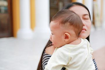Asian mother carrying her infant. Close-up.