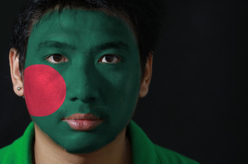 Portrait of a man with the flag of the Bangladesh painted on his face on black background, a red...