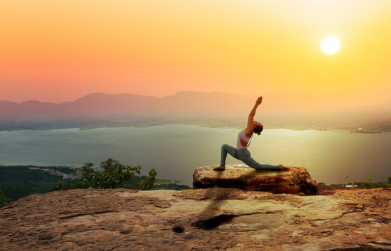 Woman practice yoga on mountain with sunset or sunrise background