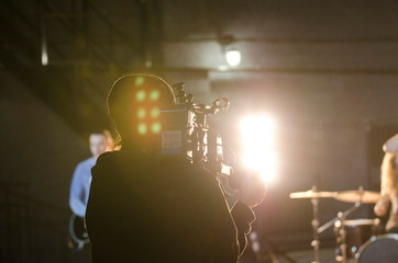 Professional videographer using cinema digital video camera for filming a music video.