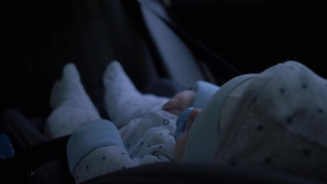 Little baby boy sitting in car seat riding in backseat of car