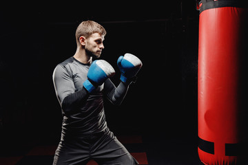 Male boxing in punching bag. Training Executes blows before fight.