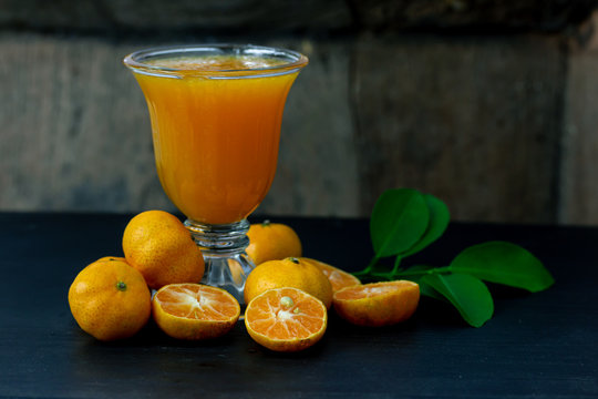 fresh Chinese orange cut and orange juice with Pumpkin Doll isolate on wood background