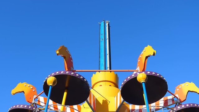 Colorful amusement park ride spinning against clear blue sky