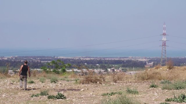 Man walking on arid land, overlooking city