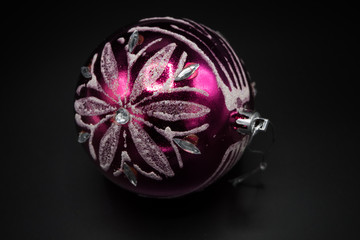 Pink and silver christmas bauble on black background.
