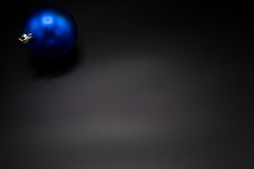 Blue christmas ball on black background. Copy scape.