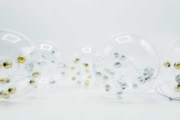 Transparent Christmas decoration balls with golden and silver spheres inside on white.