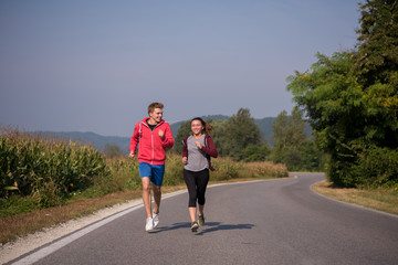 young couple jogging along a country road